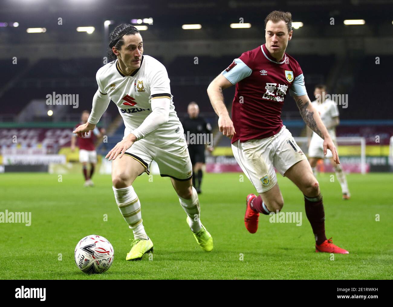 Milton Keynes Dons' George Williams (left) nd Burnley's Ashley Barnes battle for the ball during the Emirates FA Cup third round match at Turf Moor, Burnley. Stock Photo