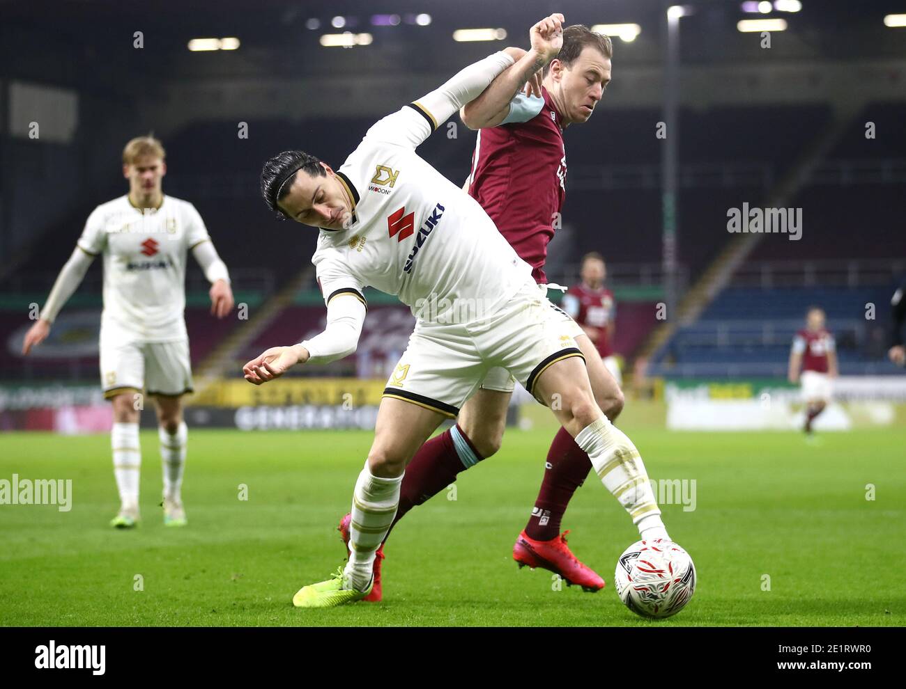 Milton Keynes Dons' George Williams (left) nd Burnley's Ashley Barnes battle for the ball during the Emirates FA Cup third round match at Turf Moor, Burnley. Stock Photo