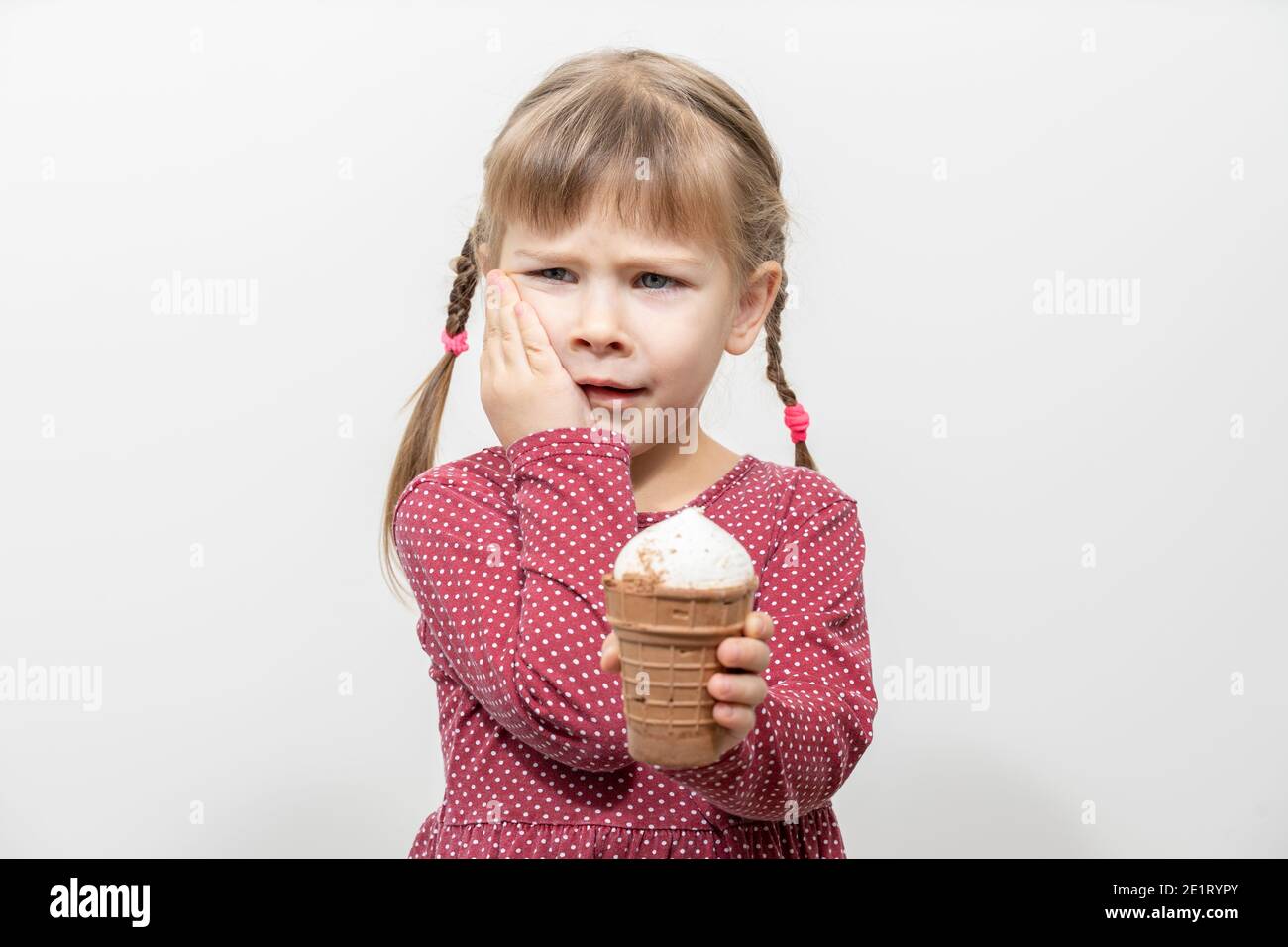 kid girl has a toothache while eating ice cream. sensitivity of teeth