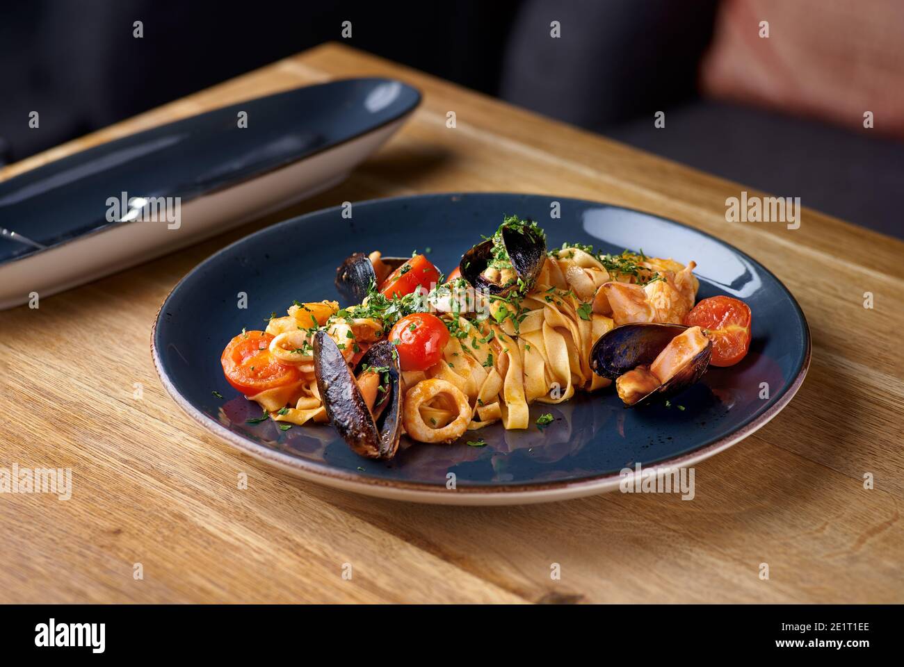 Pappardelle pasta with seafood, mussels and tomatoes on the table at restaurant, menu food