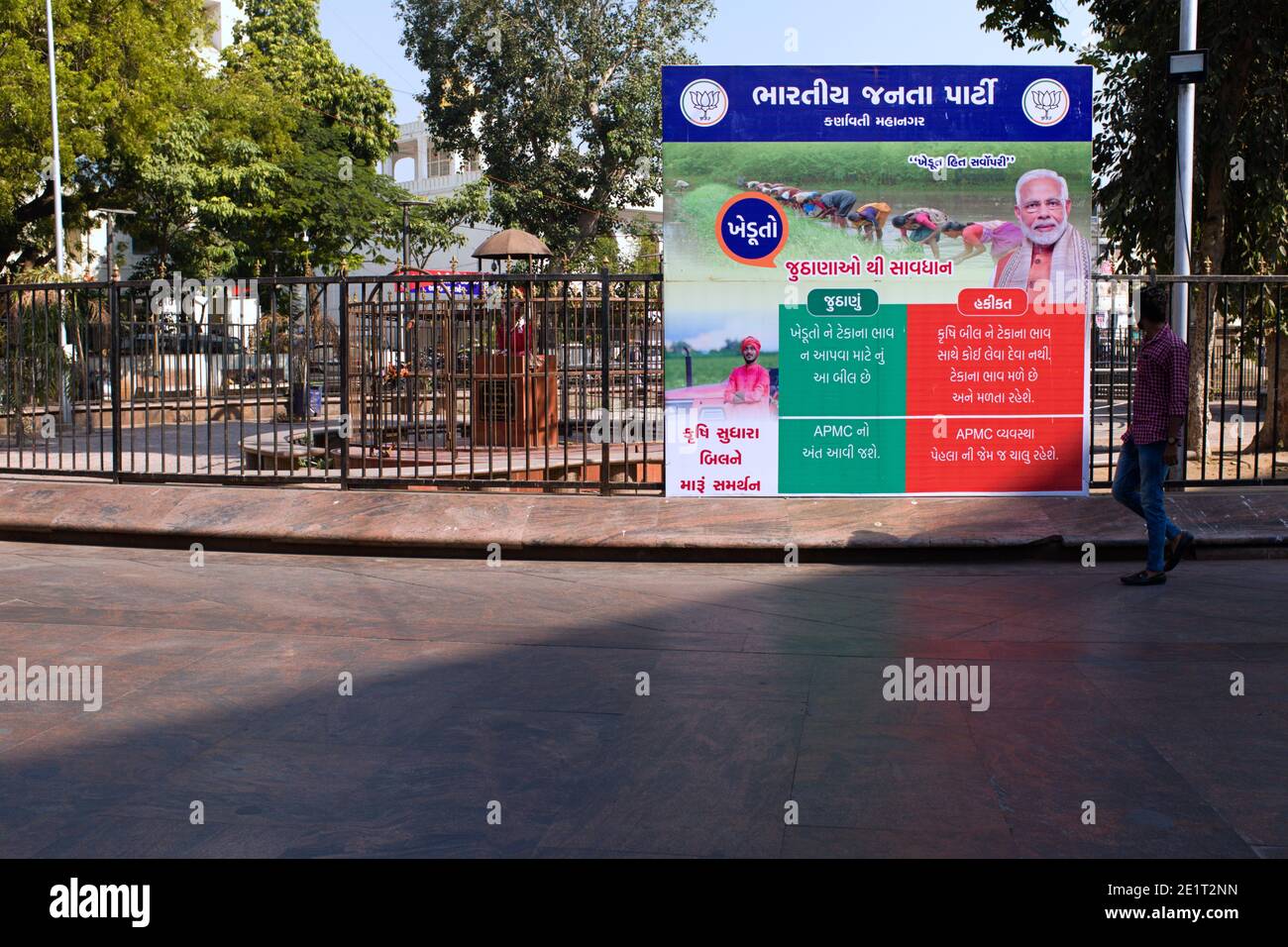 A man in Ahmedabad, Gujarat walks past a poster demonstrating 2020 farm law reforms lies versus facts put up the ruling Bhartiya Janta Party. Stock Photo
