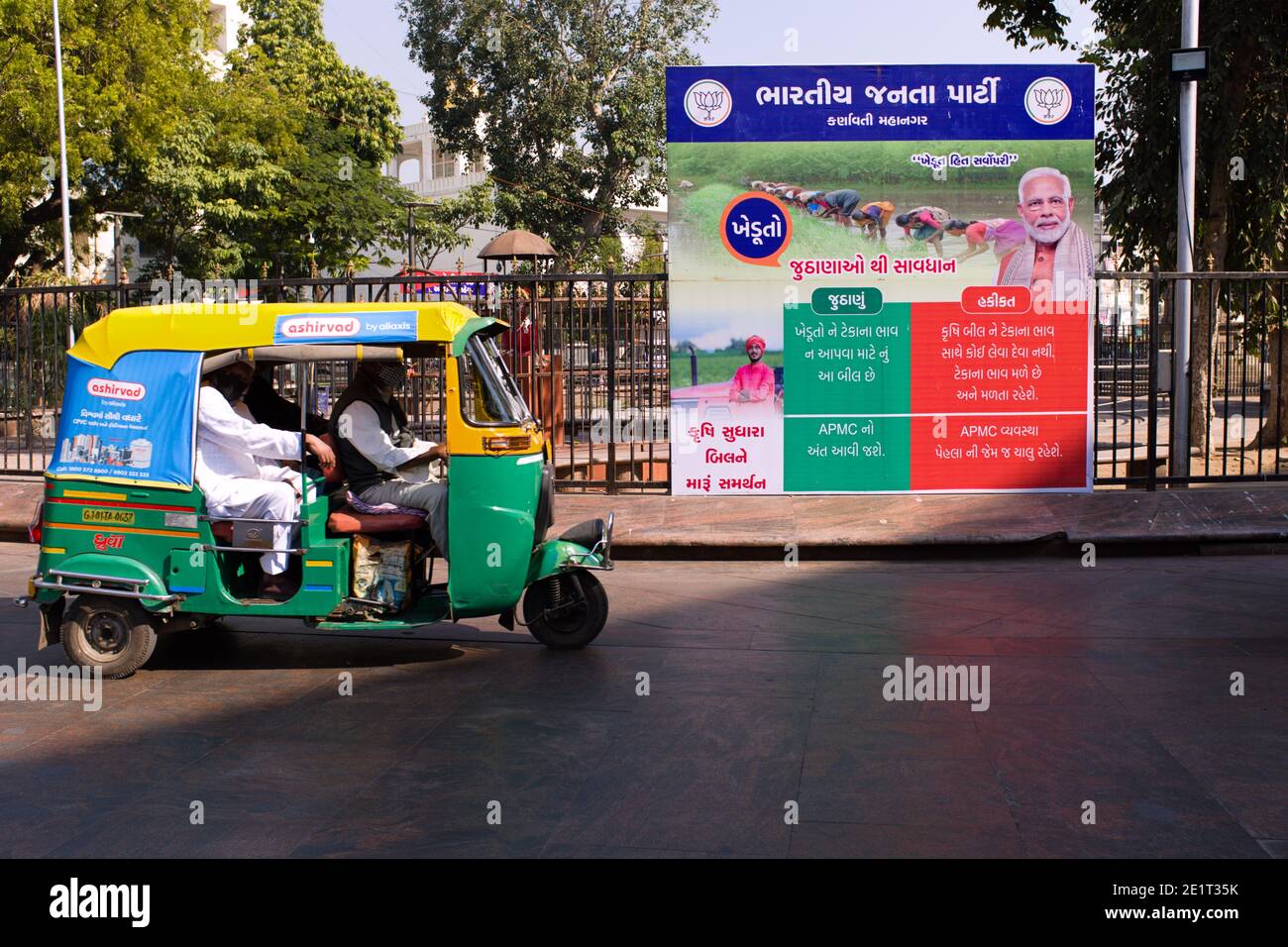 An auto rikshaw in Ahmedabad, Gujarat drives past a poster explaining 2020 farm law reforms lies versus facts put up the ruling Bhartiya Janta Party. Stock Photo