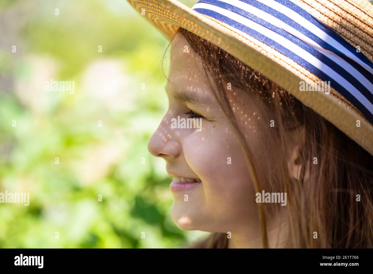 Smiling girl with long hair in a straw hat close-up in profile against ...