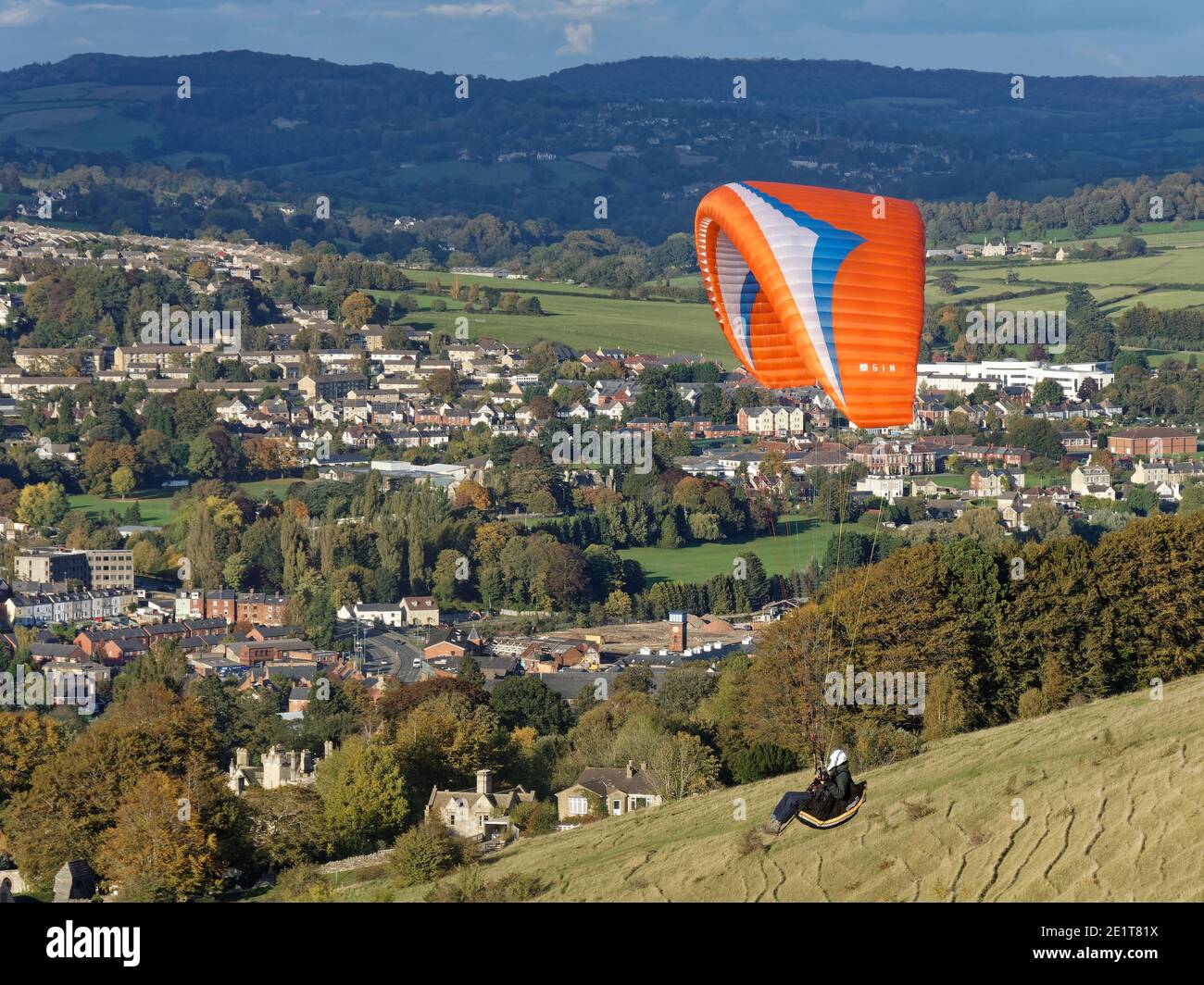 Paraglider flying from Selsley Hill, with Selsley village and Stroud in the background, Gloucestershire, UK, October. Stock Photo