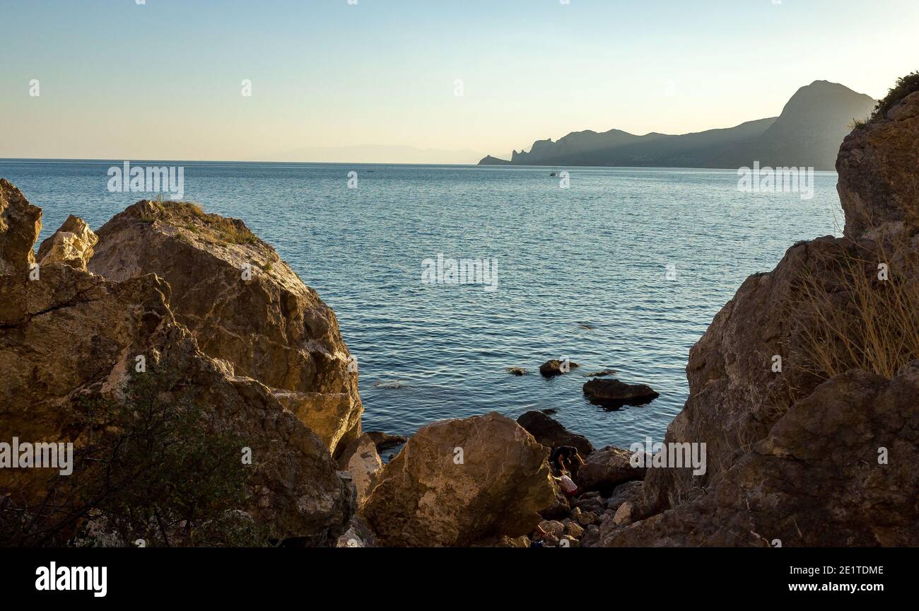 Rocks, slight sea waves at sunset on a warm summer evening. Stock Photo