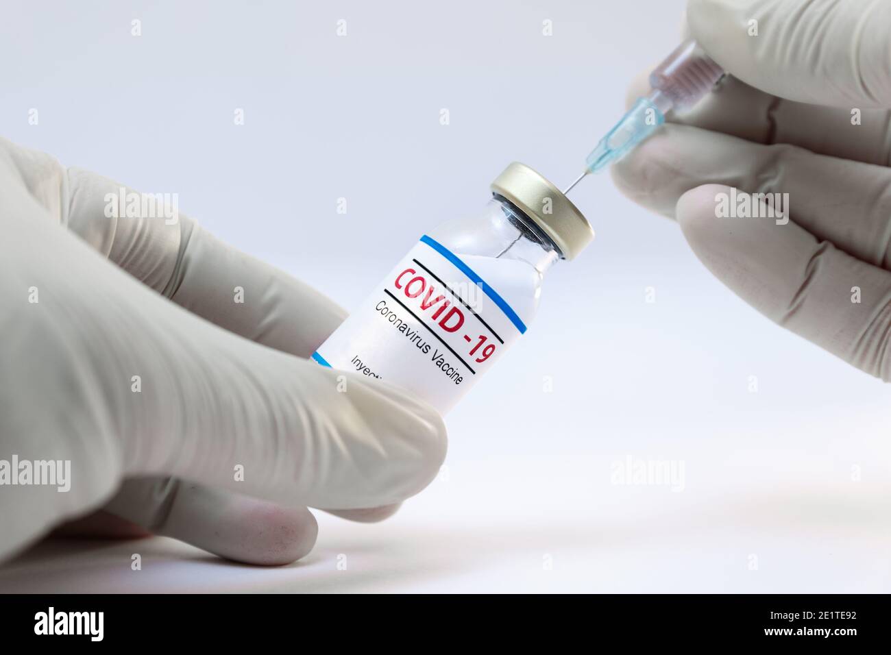Bottle of coronavirus vaccine and doctor hands with needle syringe background Stock Photo