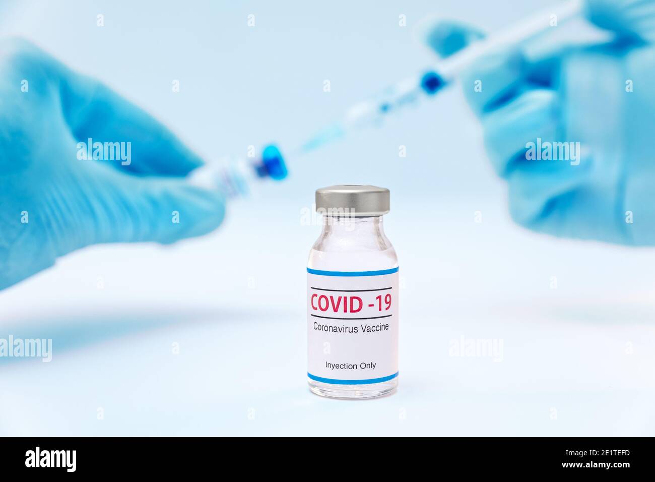 Bottle of coronavirus vaccine and doctor hands with syringe background Stock Photo