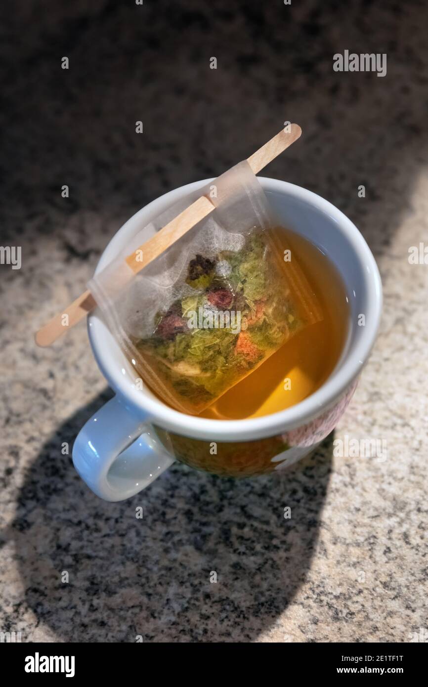A filter bag with wooden stick filled with herbal tea inside a cup Stock Photo