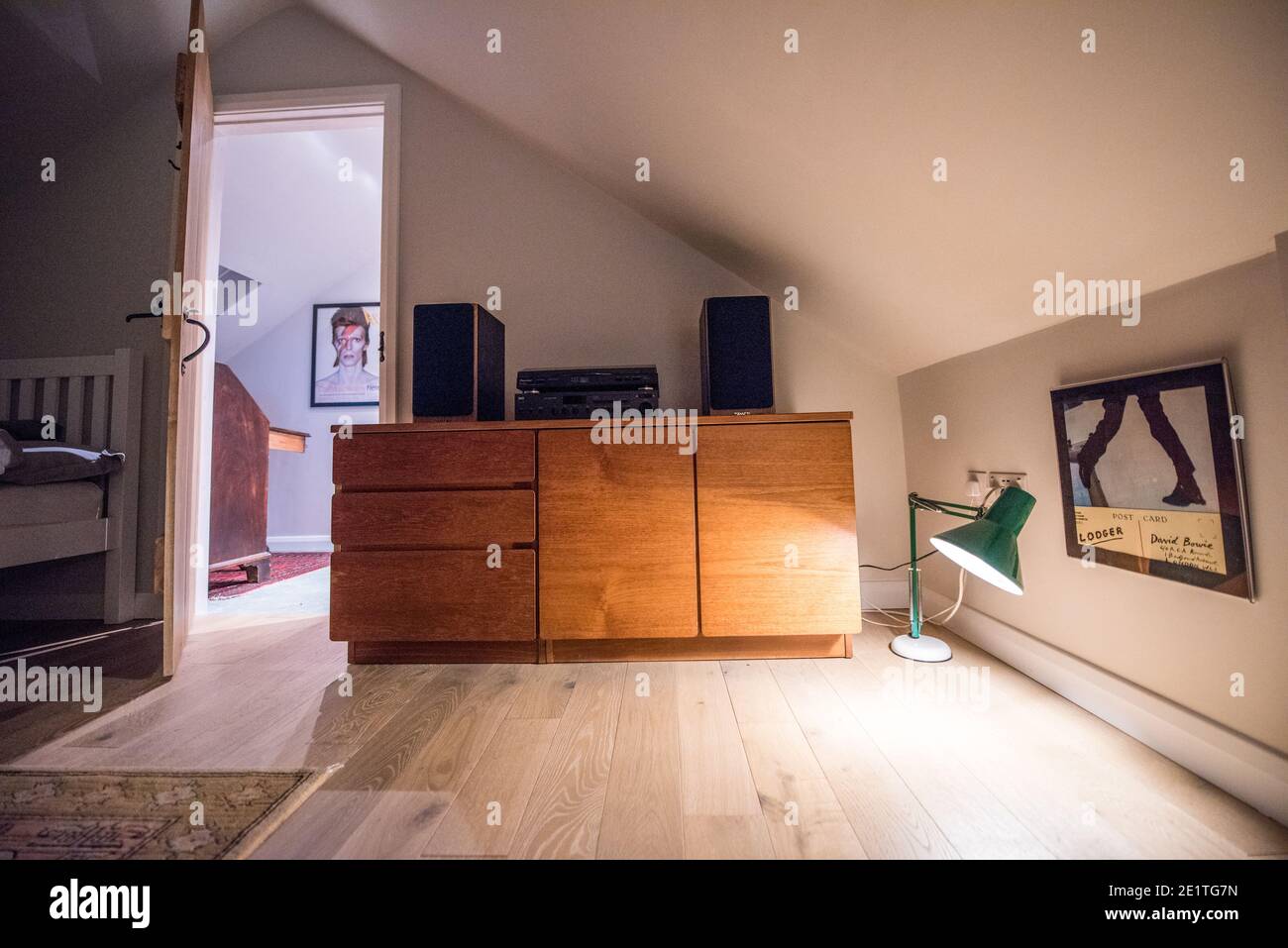 View of a loft conversion room with open oak latch door showing a wooden floor, angle poise lamp, mid century modern teak Beaver and Tapley cupboard Stock Photo