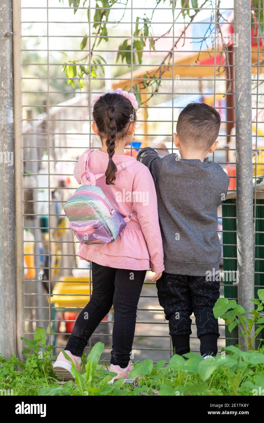 Children near the gate of closed preschool. Little kids outside school grounds. Kindergarten