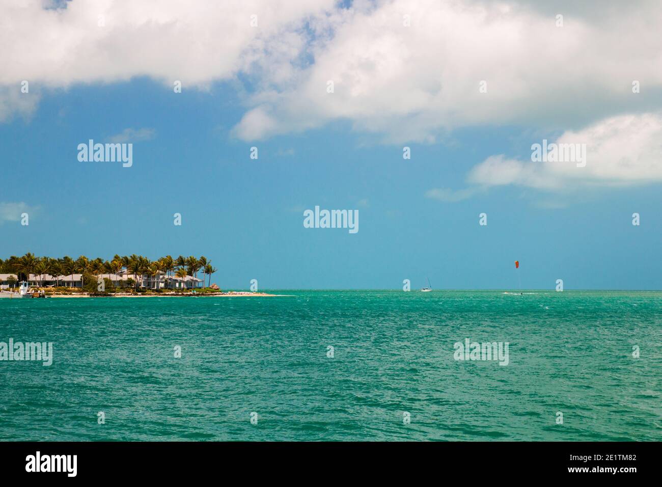 Turquoise blue sea horizon and island with sandy beach, palm trees and beach house cottages, Sunset Key in the Key West, Florida USA Stock Photo