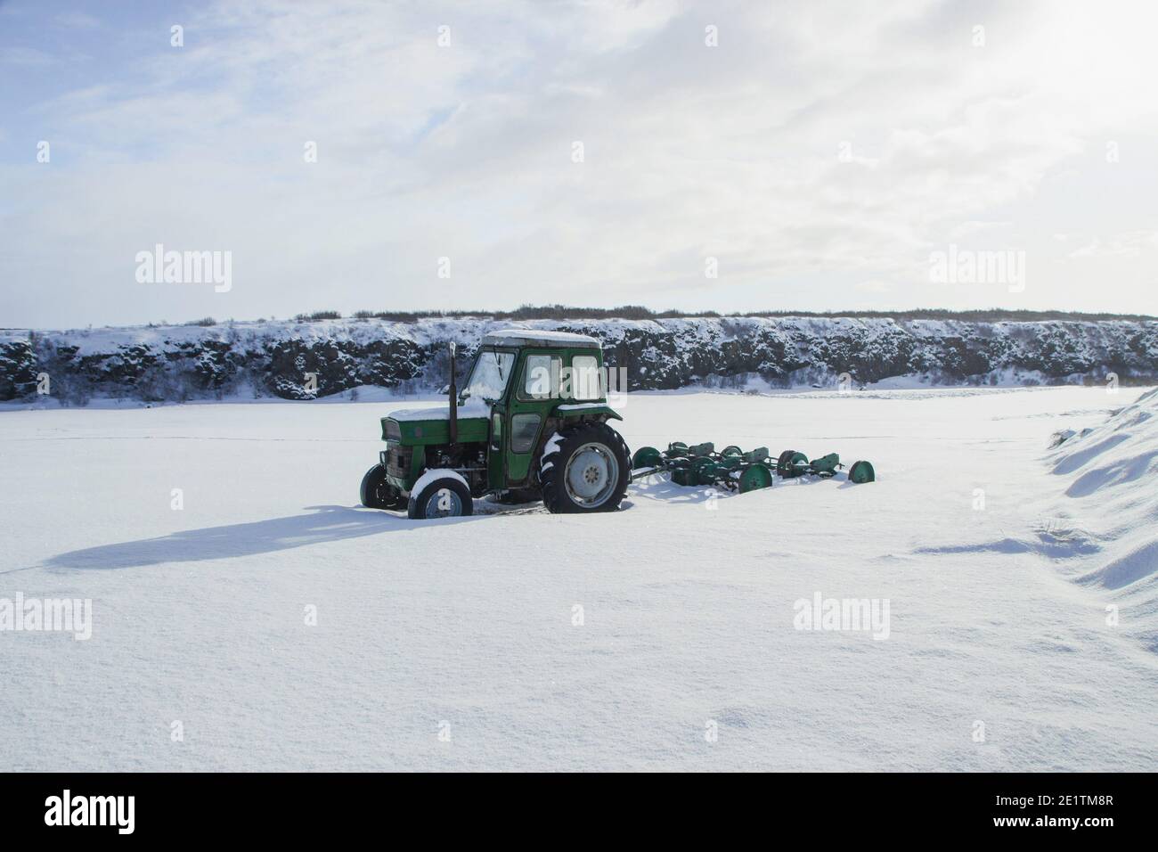 Green old tractor farm machine vehicle stuck in snow winter panorama