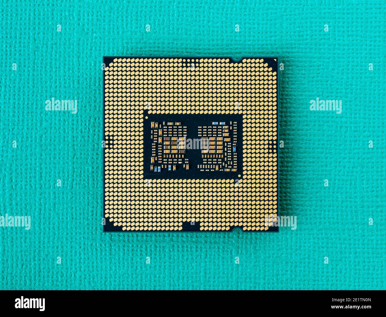 Pc micro CPU with gold plated contacts on a textured turquoise background. Modern central processing unit close-up. Desktop computer hardware macro. Stock Photo