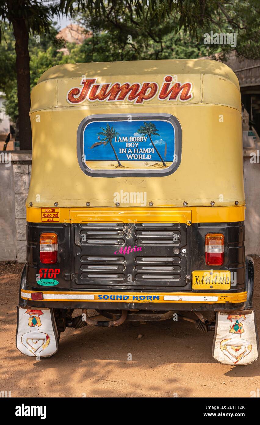 Hampi, Karnataka, India - November 5, 2013: Zanana Enclosure. Back of black-yellow tricycle taxi with colorful painted messages stands in front of wal Stock Photo
