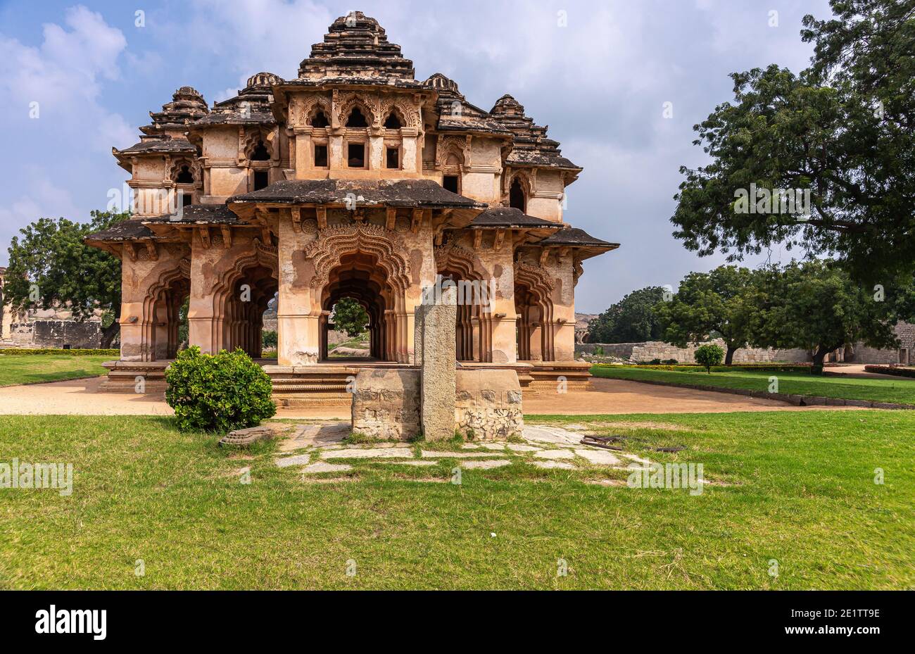 Hampi, Karnataka, India - November 5, 2013: Zanana Enclosure. Brown stone ruinous Lotus Mahal building in green park under blue cloudscape. Stock Photo
