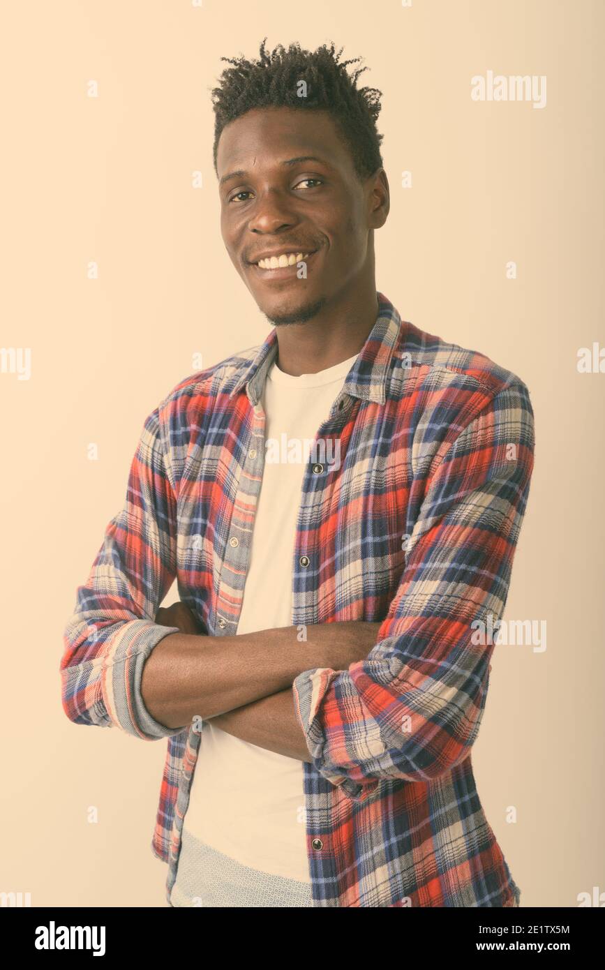 Studio shot of young happy black African man smiling with arms crossed ...