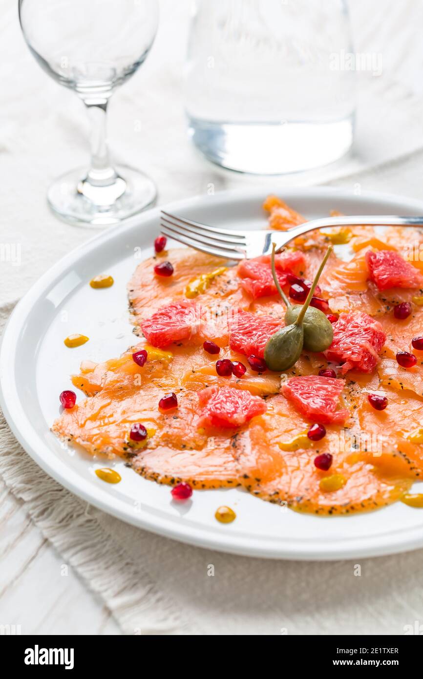 Salmon carpaccio with pink grapefruit and pomegranate on white plate Stock Photo