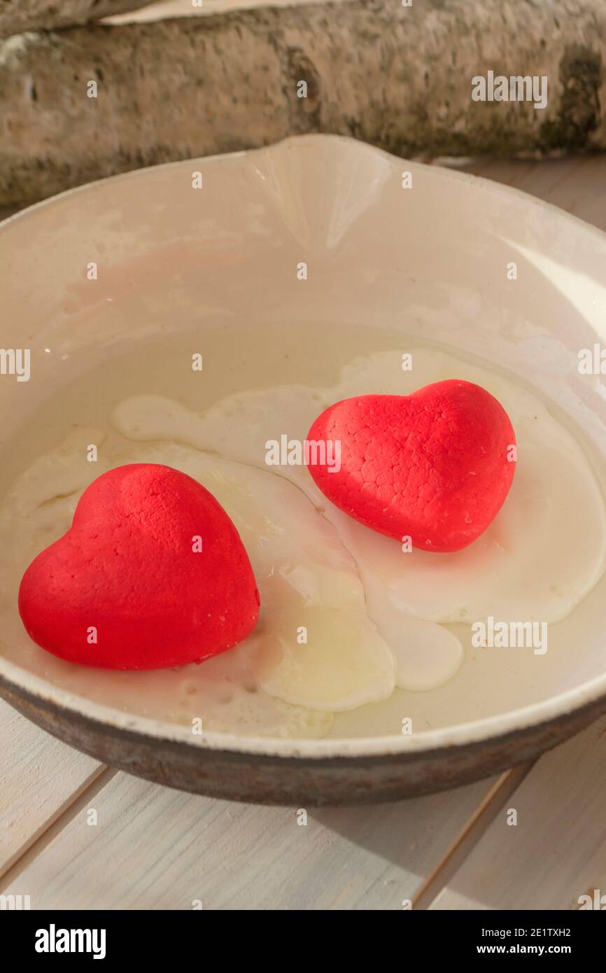 cooked egg with red hearts in a fryer, concept of belarusian revolution, vertical image Stock Photo