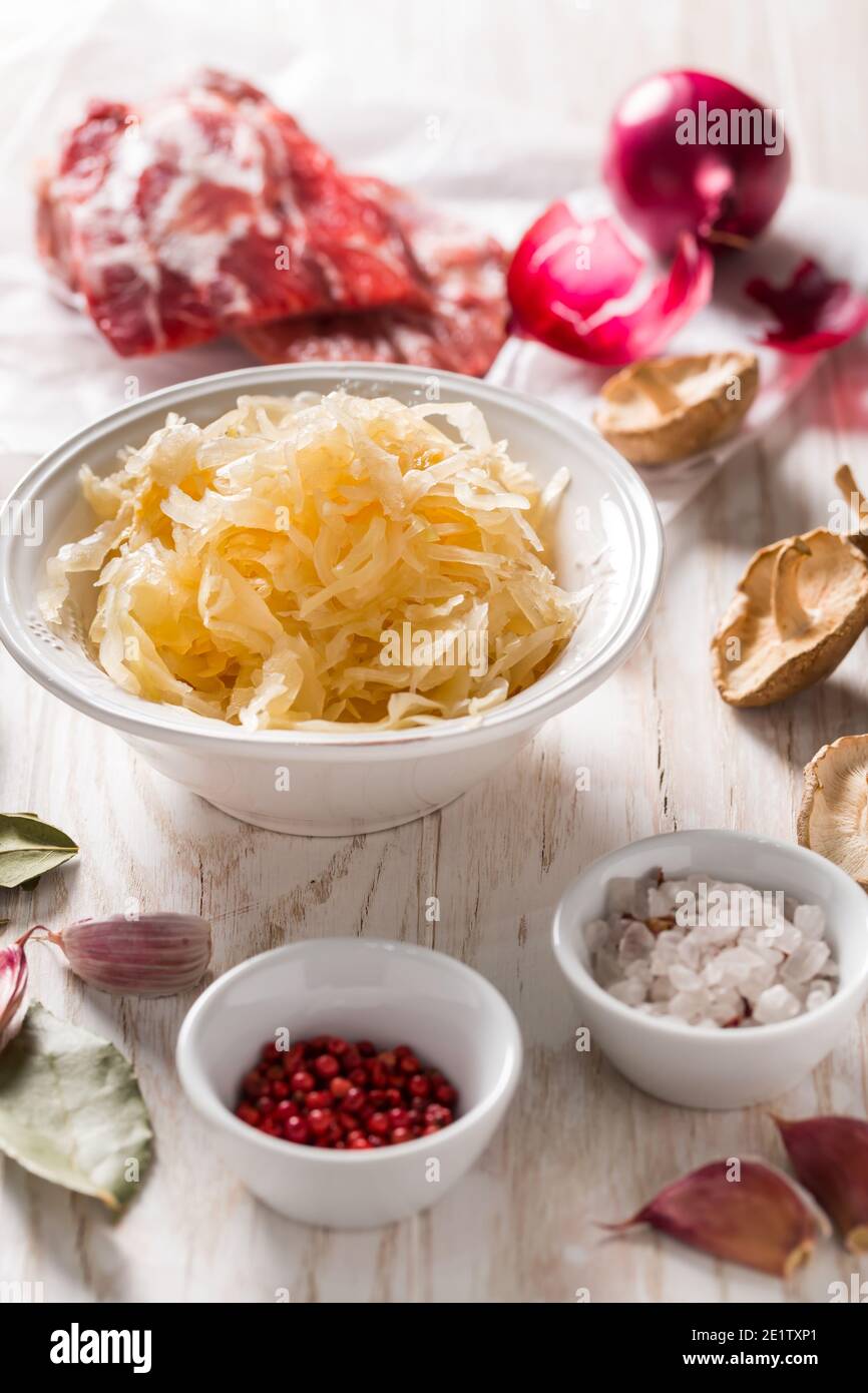 Ingredients for hearty sour cabbage soup (sauerkraut soup) with meat, onioc, garlic and spicies on wooden table Stock Photo