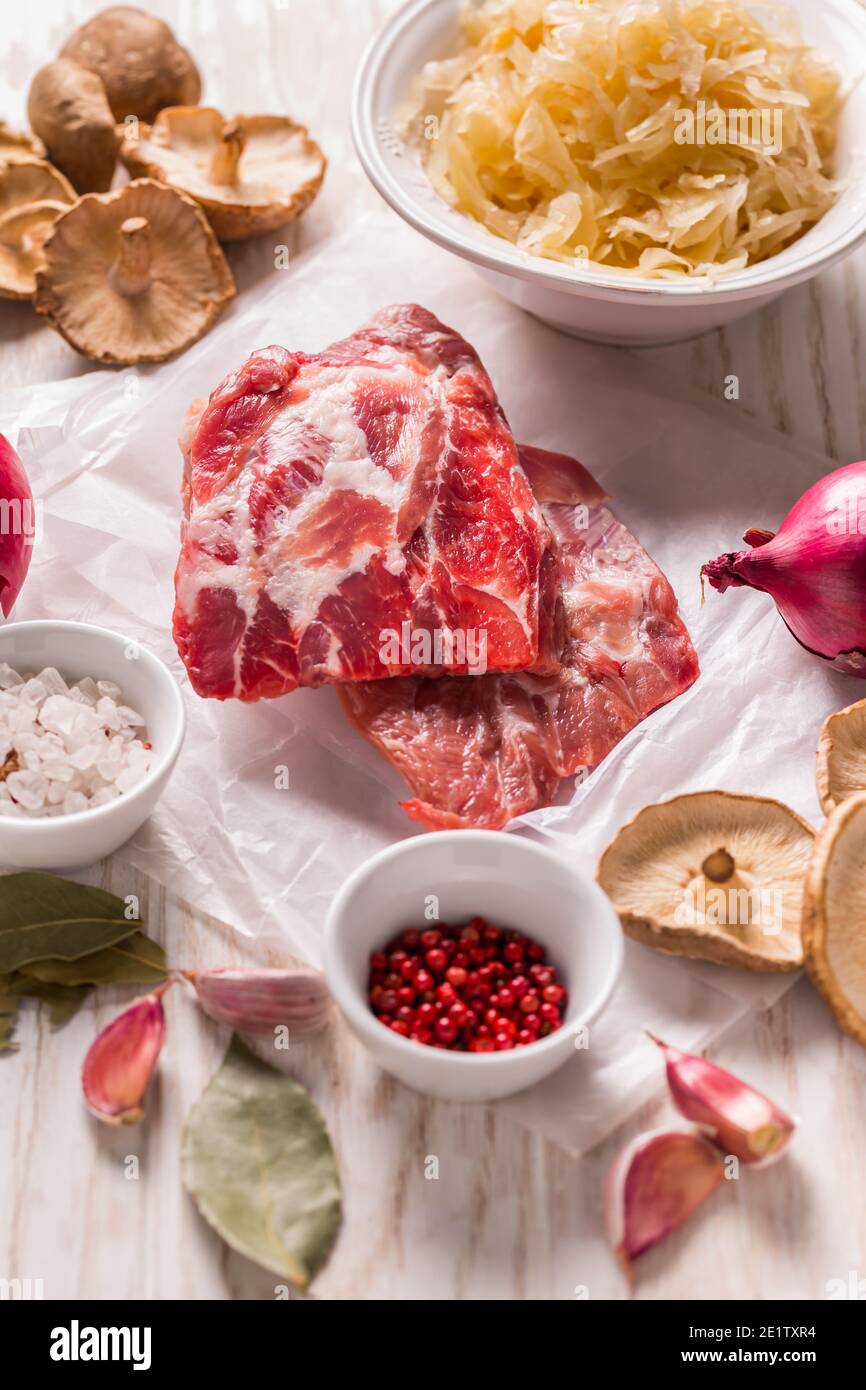 Ingredients for hearty sour cabbage soup (sauerkraut soup) with meat, onioc, garlic and spicies on wooden table Stock Photo
