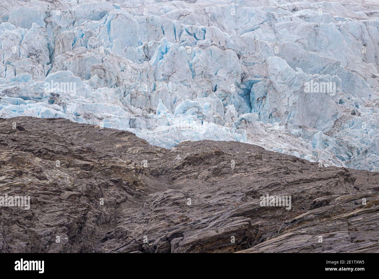 Polar bear resting on a ridgeline, high up on a hillside near Pyramiden on Svalbard. Nordenskjoldbreen in the background. Stock Photo
