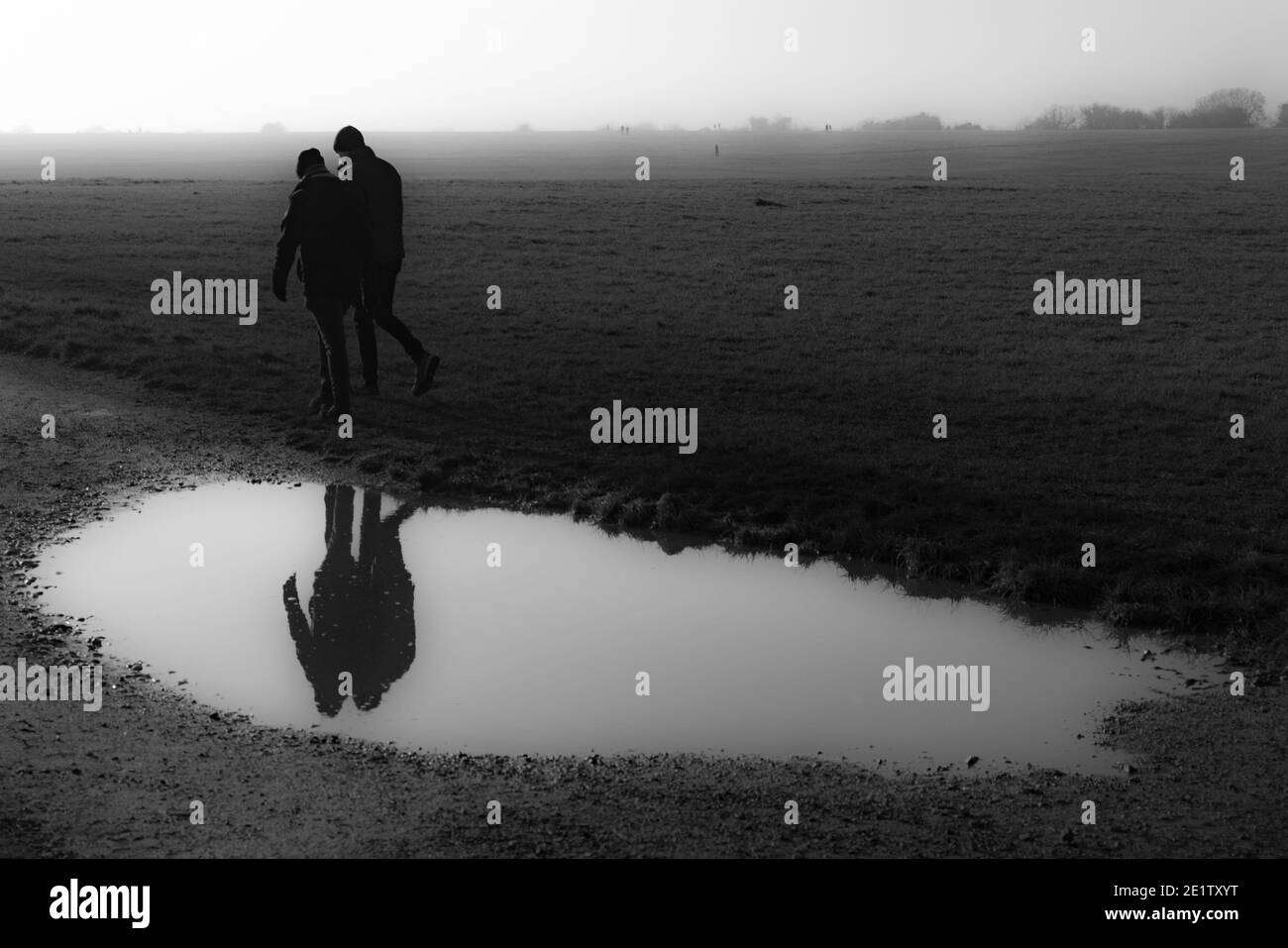 Couple Passing   a Puddle in Winter Stock Photo