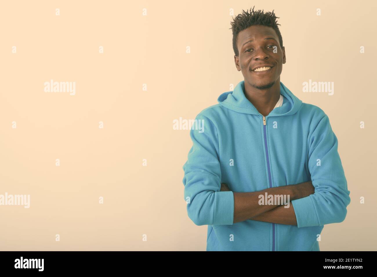 Studio shot of young happy black African man smiling with arms crossed ...