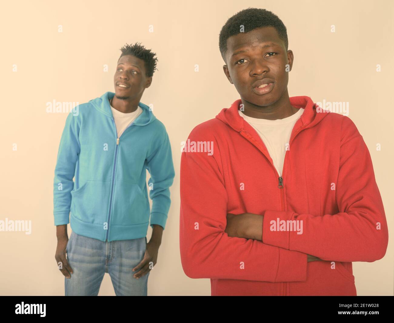 Studio shot of young black African man with arms crossed and one happy ...