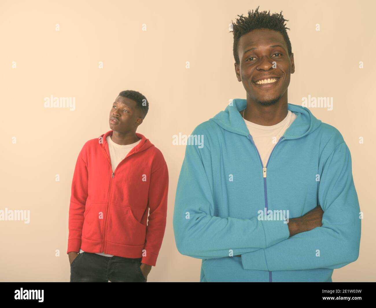 Studio shot of young happy black African man smiling with arms crossed ...