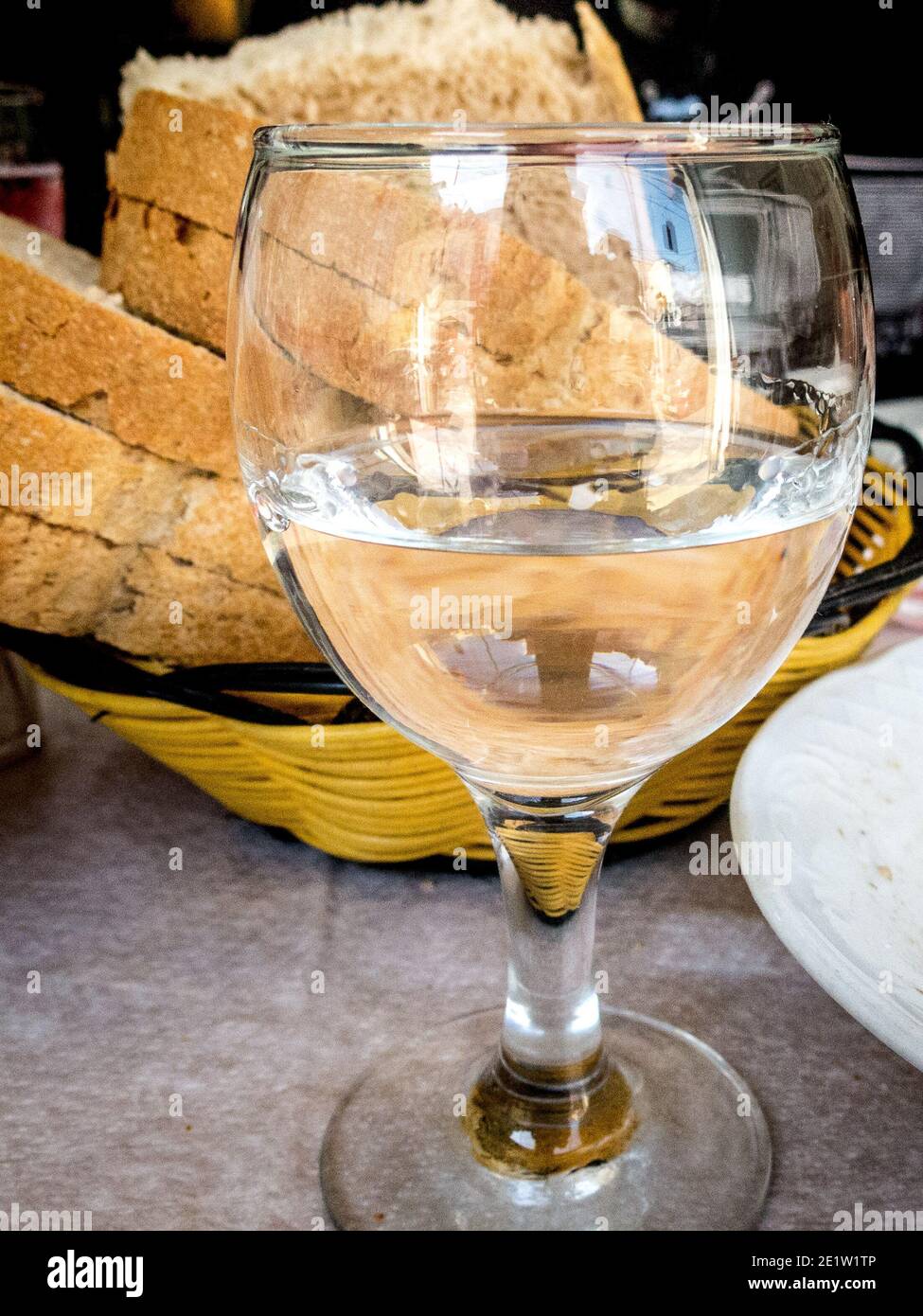 Albanian Raki, a clear alcohol distilled from different kinds of fruit, served in a wine glass with a side of fresh bread. Stock Photo