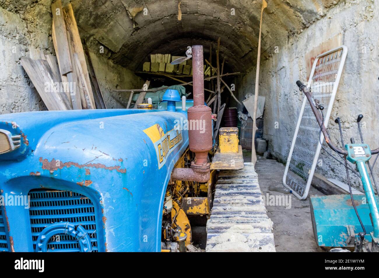 A blue tractor parked inside a repurposed bunker. Albania. Communist-era bunkers were built by dictator Enver Hoxha during the Cold War. Stock Photo