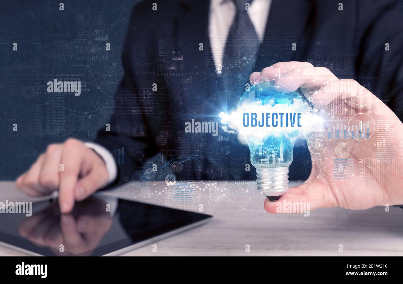 Businessman holding a light bulb with OBJECTIVE inscription, new ...