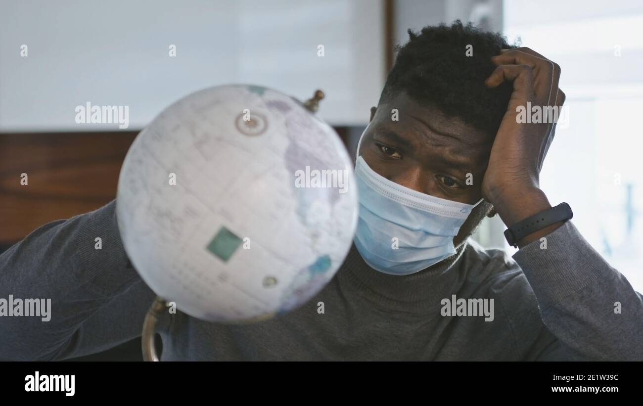 lonely sad african american black man rolling globus in his home with  medical mask. Traveling during covid-19 pandemic. High quality photo Stock  Photo - Alamy