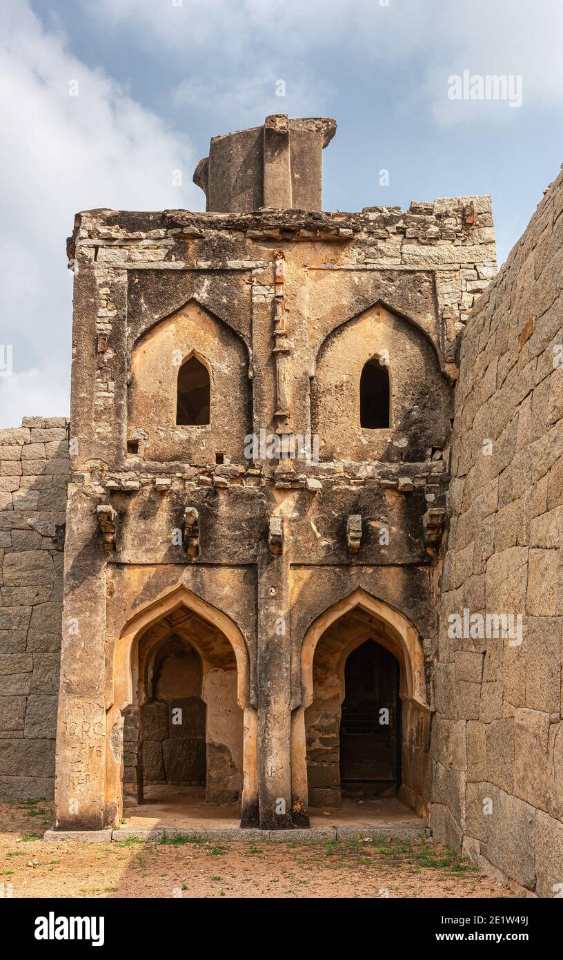 Hampi, Karnataka, India - November 5, 2013: Zanana Enclosure. Brown stone ruinous eastern watchtower isolated against wall under blue sky. Stock Photo