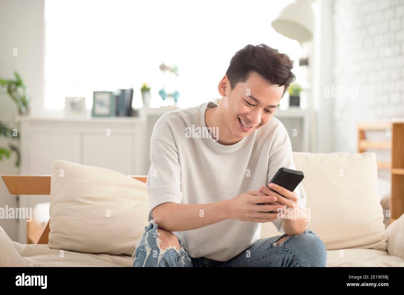 happy young man  looking at cell phone in living room at home Stock Photo