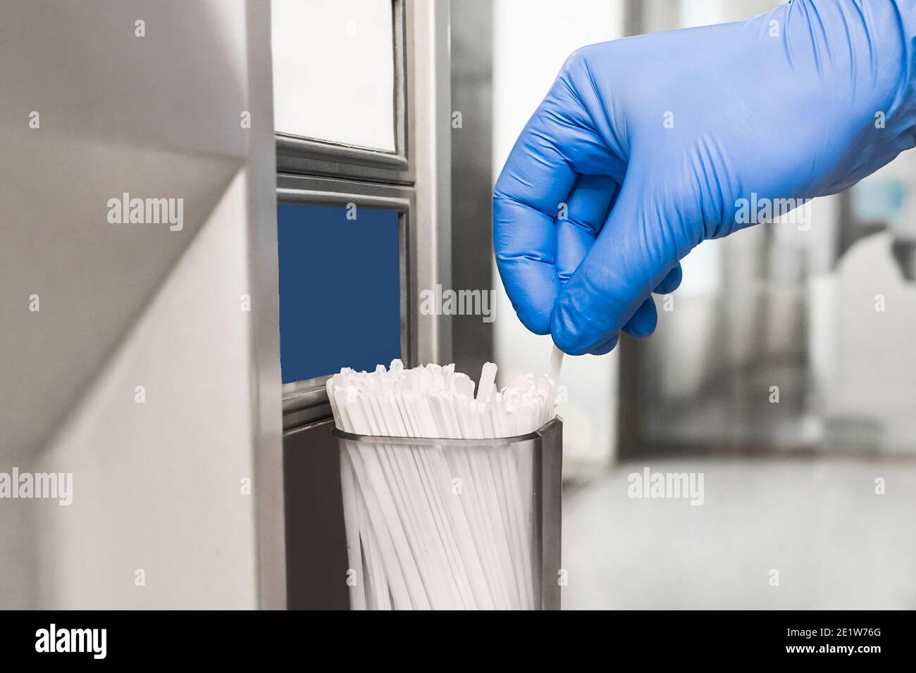 A man's hand in a protective medical glove takes a stick for stirring coffee or tea from a special machine, close-up. Stock Photo