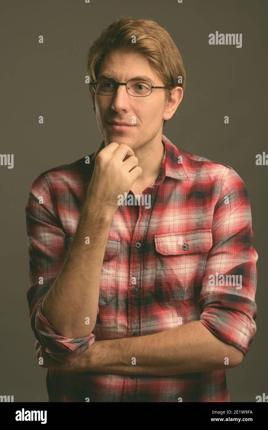 Handsome man wearing eyeglasses against gray background in black and white Stock Photo