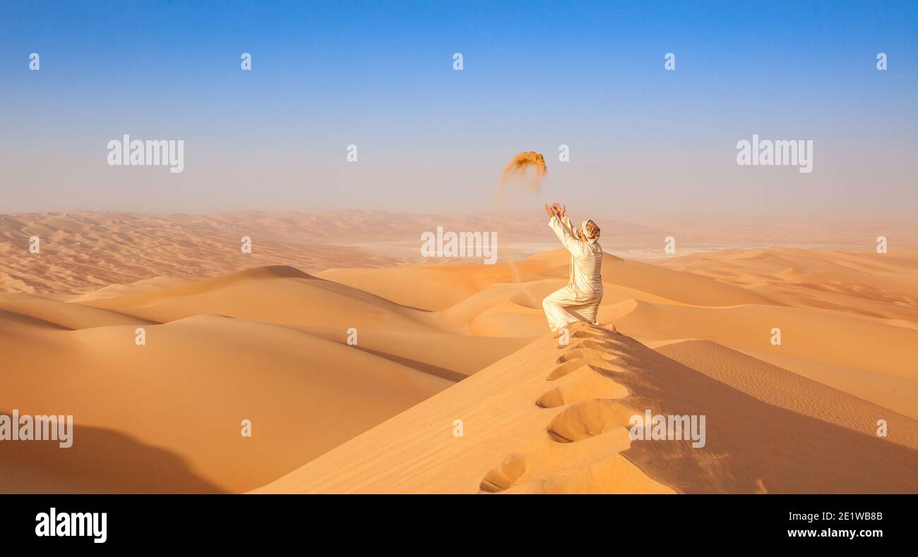 arab man in tradition outfit on a Dune in arabian Desert Stock Photo