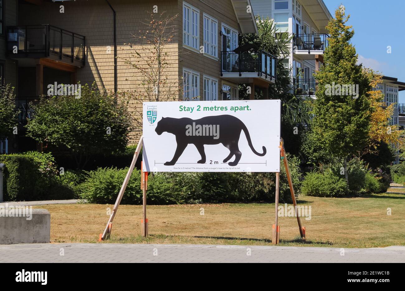 Social distancing sign with a painted black cougar on the board at the entrance of the park. Stock Photo
