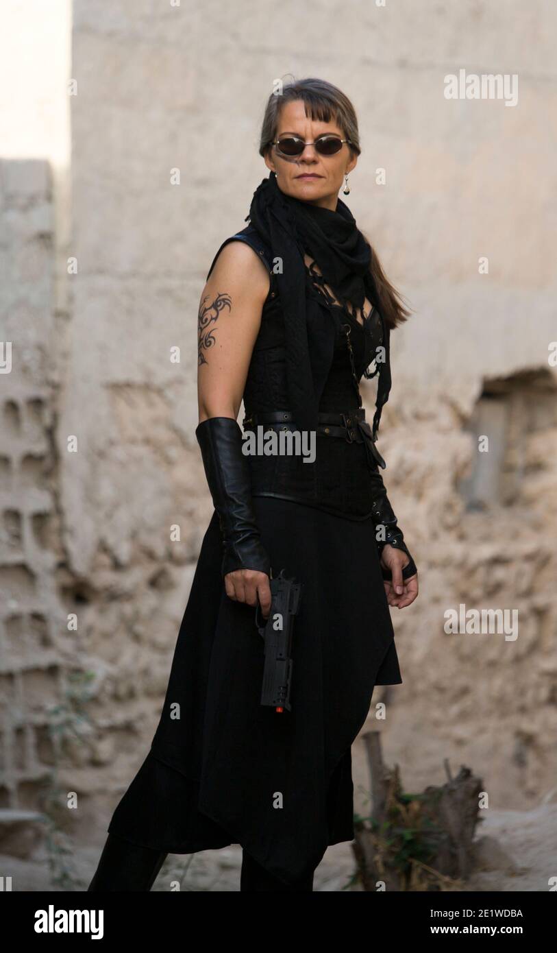 Middle Aged Woman Wearing steampunk costume of freedom Fighter in her old  destroyed village Stock Photo