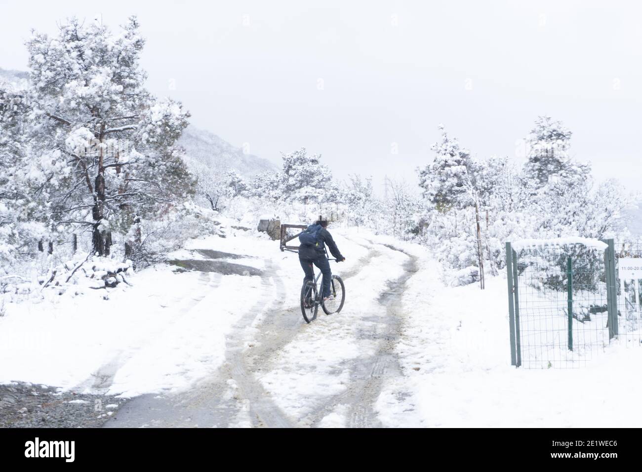 A young man tries to ride a bike on a snowcovered mountain road