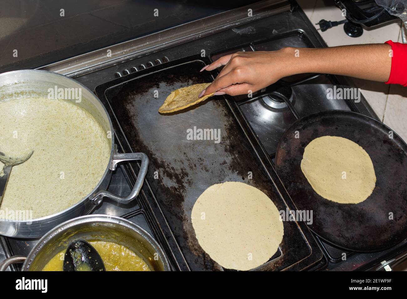 https://c8.alamy.com/comp/2E1WF9F/hand-of-a-young-woman-taking-out-a-tortilla-from-the-comal-in-her-kitchen-house-2E1WF9F.jpg