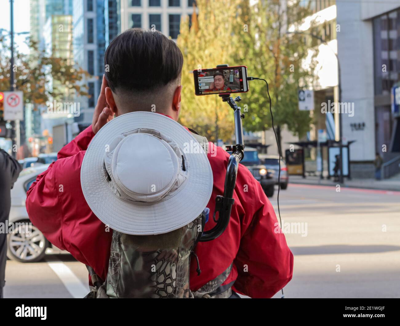 A young man uses his smart phone holder on the back equipment to communicate with friends. Vancouver,BC Stock Photo