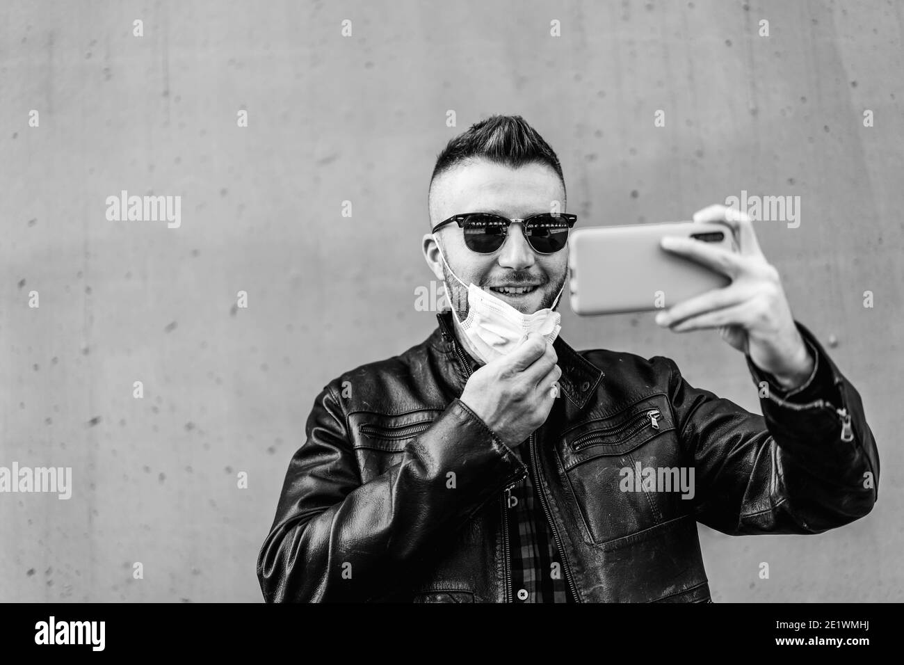 Cool man with big smile wearing open face protective mask during  coronavirus outbreak - Smiling hipster man video calling against wall  background – Te Stock Photo - Alamy