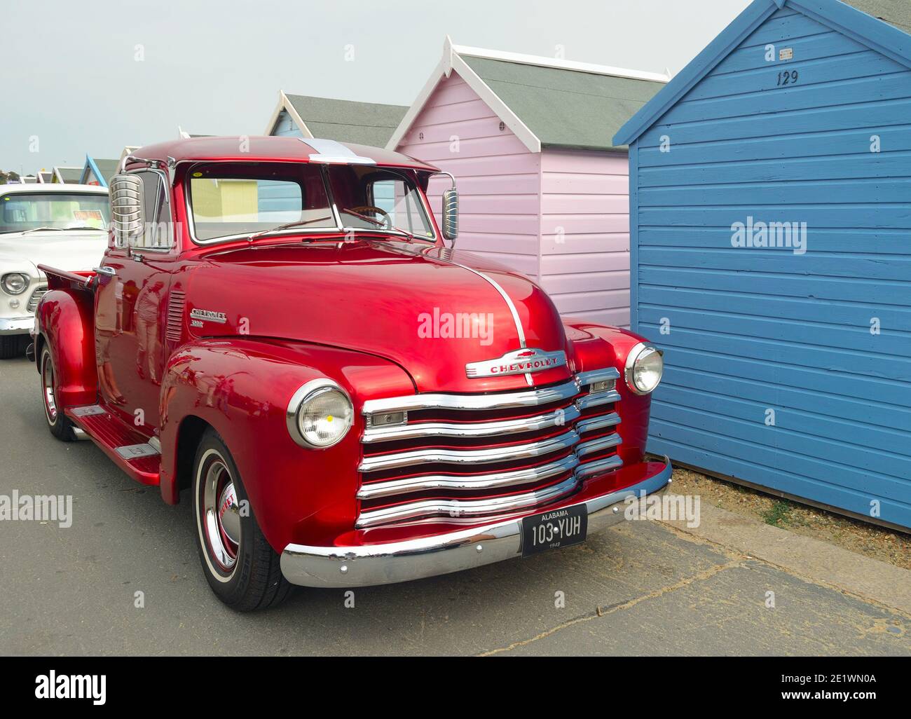 Classic Red  Chevrolet 3100 pickup truck on seafront promenade in front of beach huts. Stock Photo