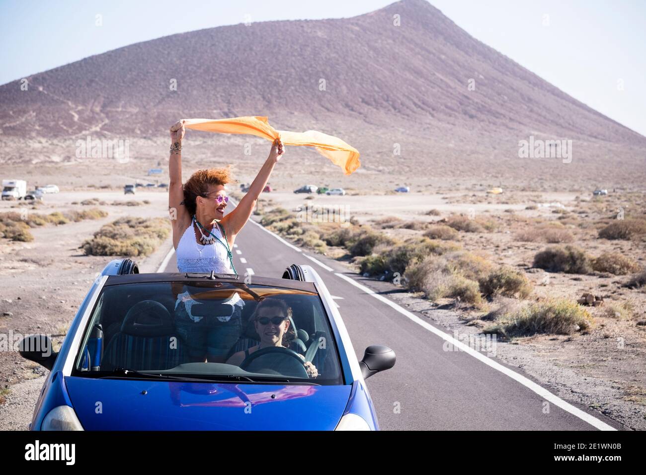 Couple of happy woman travel together with convertible car on a long road having fun and enjoying the freedom - people female power traveling with veh Stock Photo