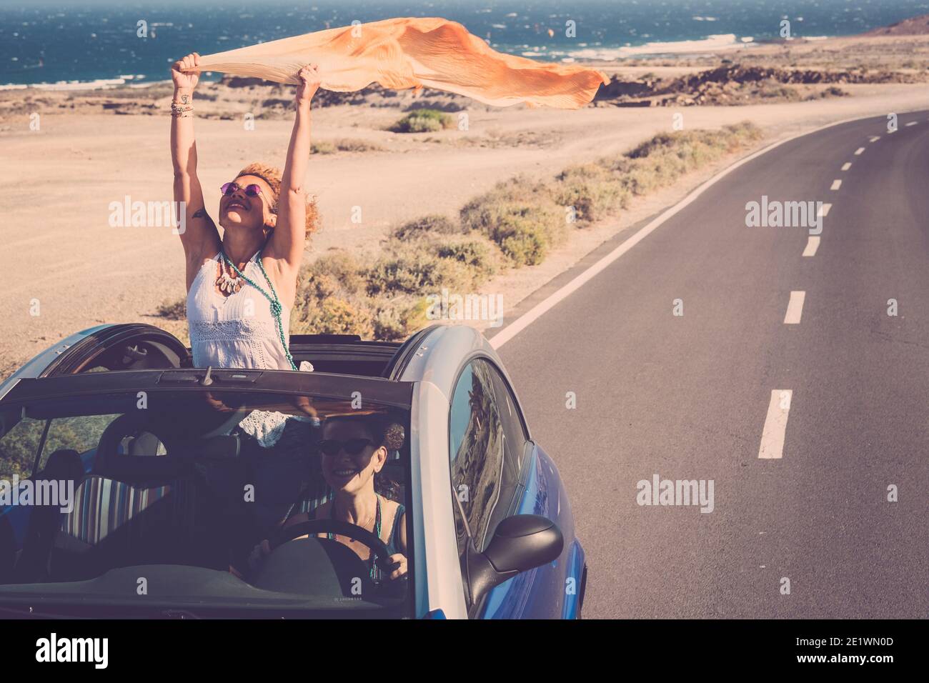 Concept of travel happiness with adult beautiful couple of women driving a car and enjoying the freedom together in friendship - people on the road wi Stock Photo