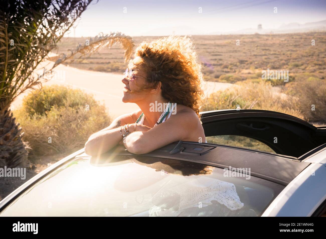Cheerful woman smile and enjoy freedom traveling outside a convertible car under the summer sun - holiday vacation lifestyle concept for beautiful you Stock Photo