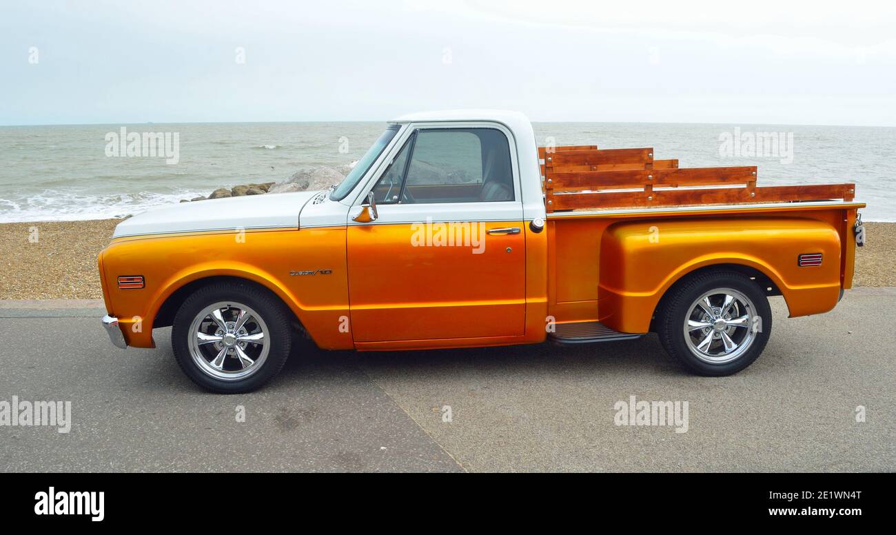 Classic Gold and white pickup truck on seafront promenade with sea in background Stock Photo