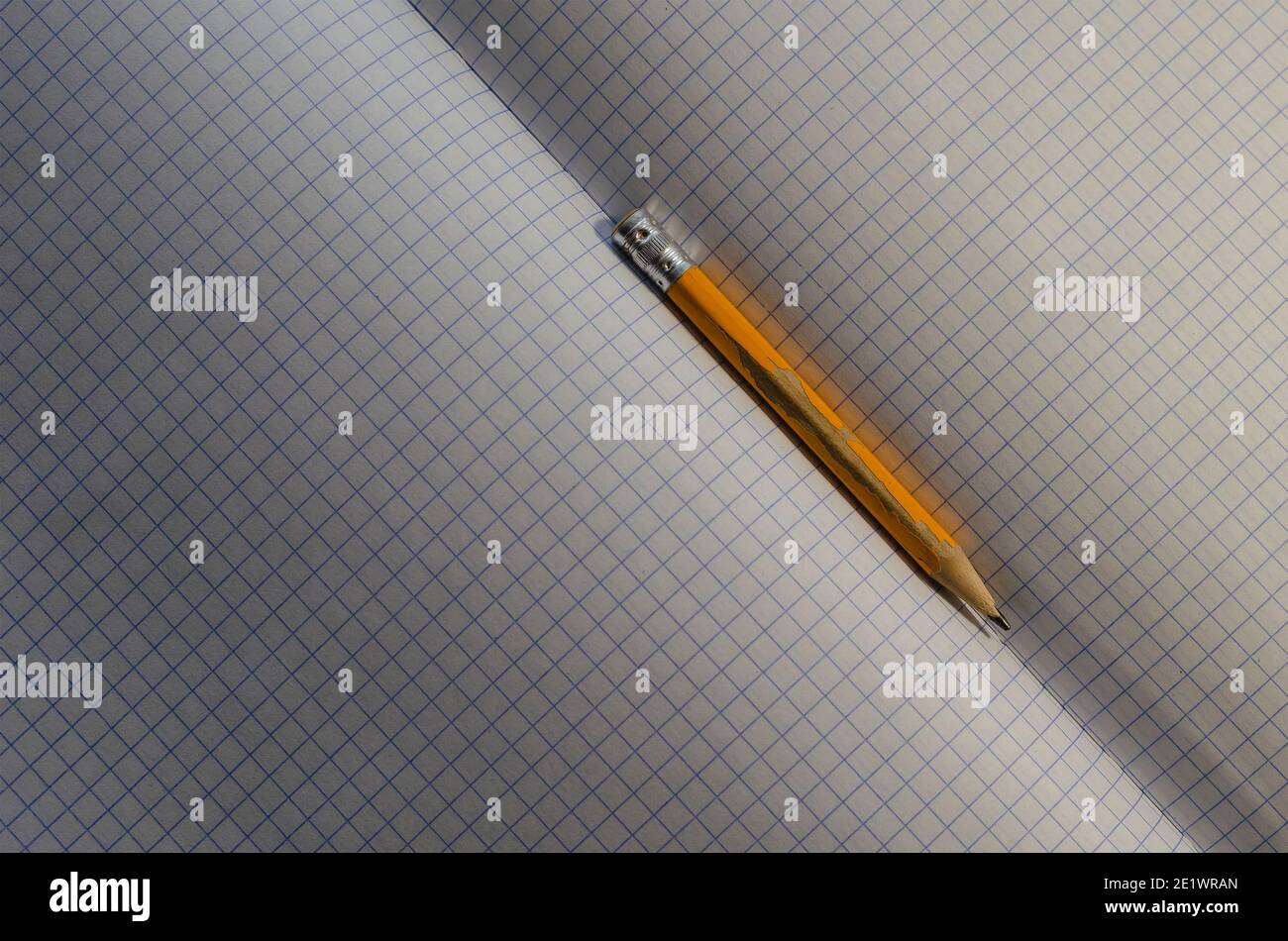 Engineering, accounting, business, education concept. Close-up of an old yellow wooden pencil on blank sheets of an open squared notebook. Selective f Stock Photo